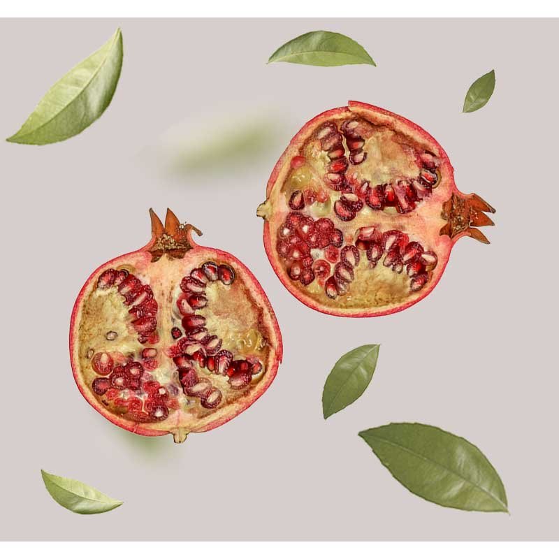 Granatapfelhälften mit saftigen Kernen und grünen Blättern, symbolisierend die natürlichen Inhaltsstoffe des RAU Beyond Herbal Tonic für Hautpflege.