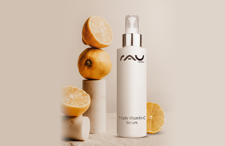 rau-cosmetics-triple-vitamin-c-serum-b Flasche mit RAU Triple Vitamin C Serum, umgeben von frischen Zitronen, auf neutralem Hintergrund, betont die Vorteile von Vitamin C für die Hautpflege im Sommer.