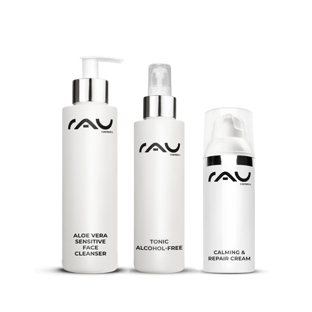 Three care products by RAU Cosmetics for sensitive skin: Aloe Vera Sensitive Face Cleanser, alcohol-free tonic, and Calming & Repair Cream, in elegant white bottles with clear labeling.