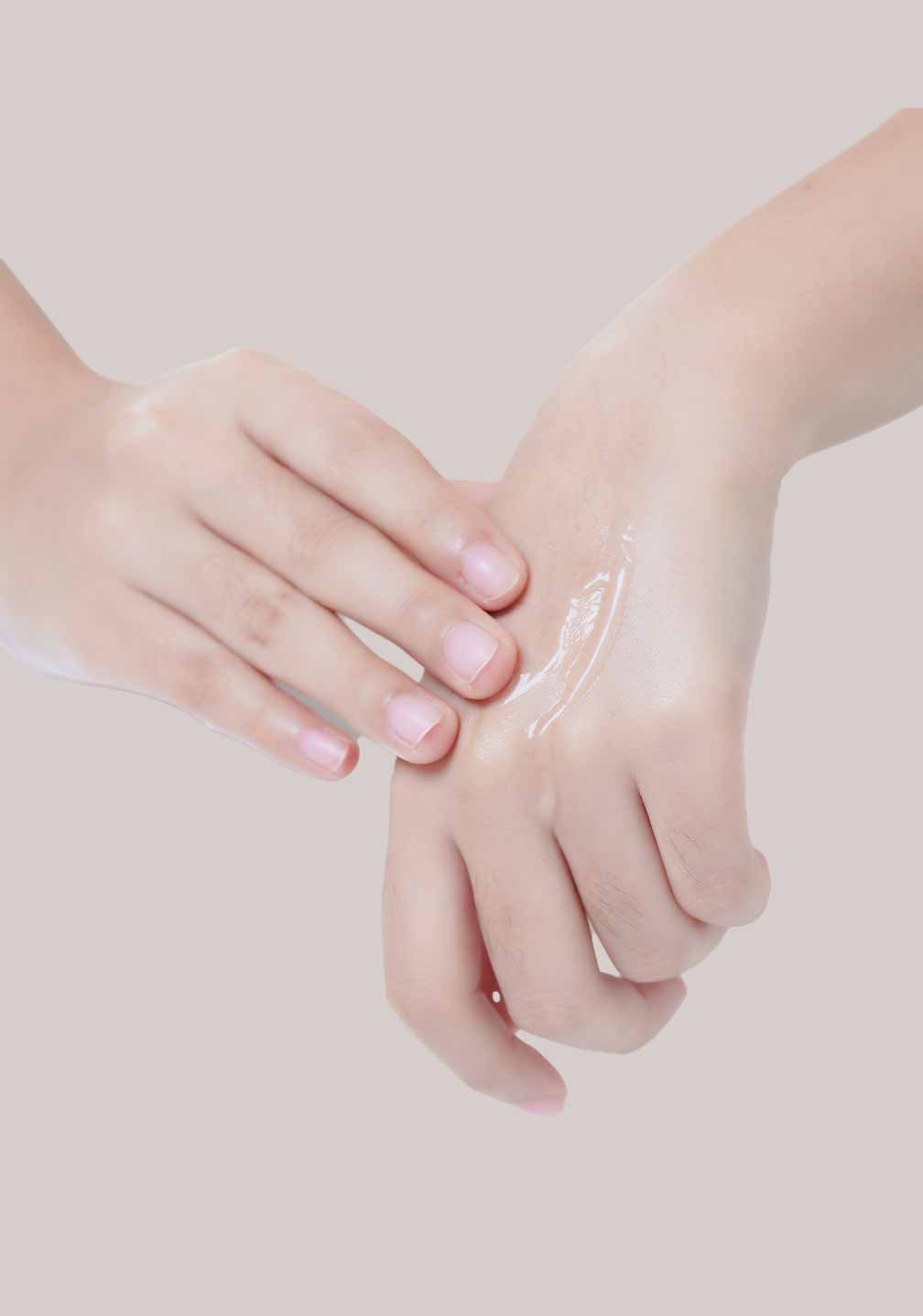 Zwei Hände applizieren hautpflegendes Lotionprodukt, vor minimalistischem Hintergrund, RAU Cosmetics Handpflege.