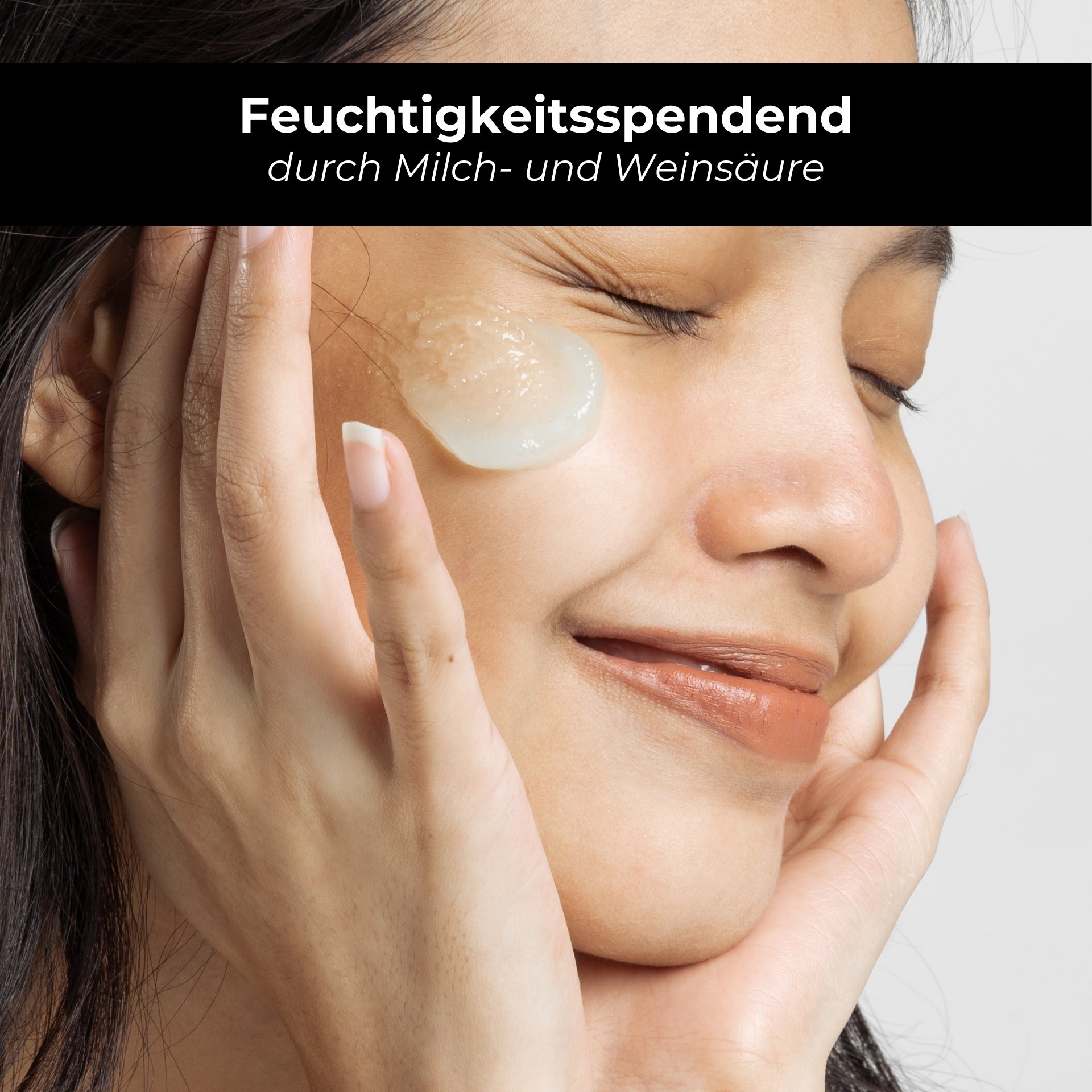 Frau mit feuchtigkeitsspendendem Gel auf dem Gesicht, lächelnd, zeigt Anwendung von Hautpflegeprodukten mit Milch- und Weinsäure.