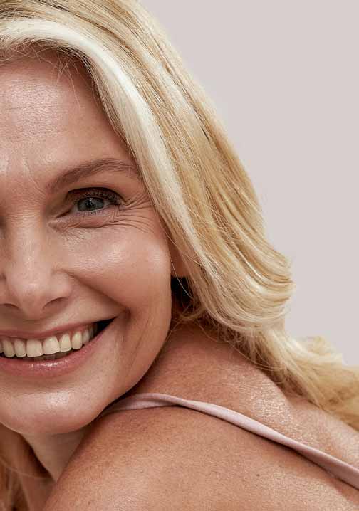 Blonde Frau lächelt vor hellem Hintergrund und wirbt für die Anti-Aging Caviar Lifting Ampoules von RAU Cosmetics für reife Haut.