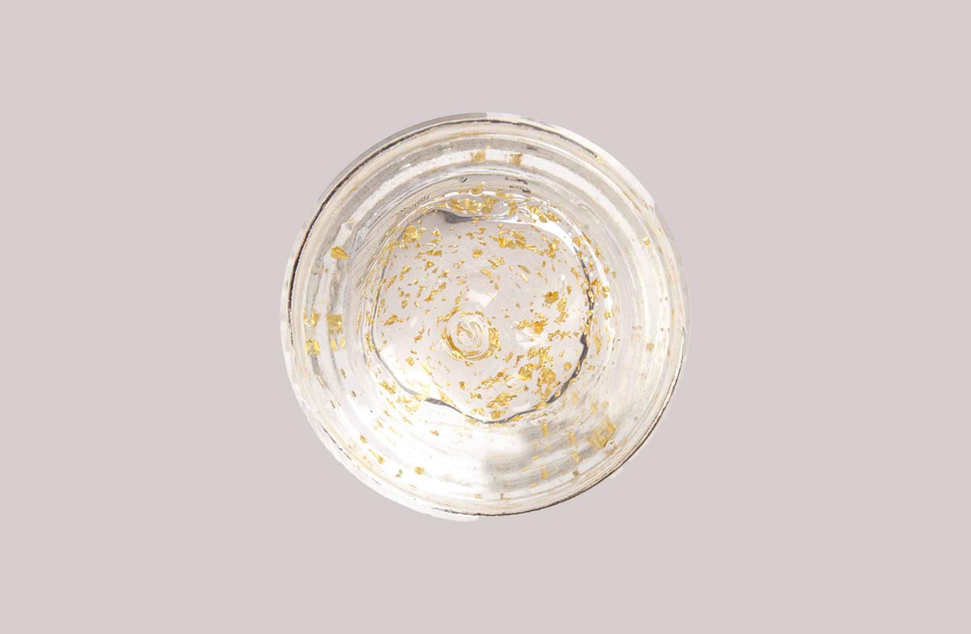 Leere Glassschale mit goldenen Partikeln, ideal für RAU Cosmetics' Golden Hyaluron Gel.