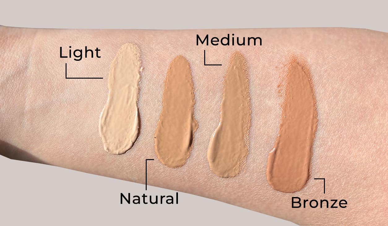 Farbmuster von vier BB-Creme-Farbtönen mit den Bezeichnungen Hell, Natürlich, Mittel und Bronze auf einem Hautton, die Möglichkeiten zum Erreichen eines ebenmäßigen, strahlenden Teints zeigen.